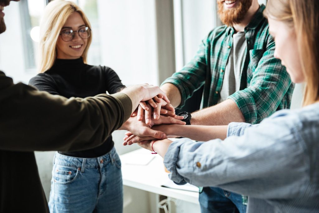 About Us 1 colleagues in office holding hands of each other PWVQD3F